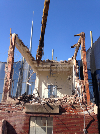 Excavator tearing down building